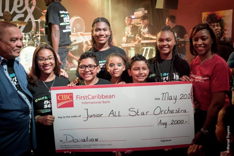 Potrèt 1 D.r.p.d. Sr. Feko Gomes i hóbennan di Junior All Star Orchestra huntu ku Sra. Lysaira Ortela di CIBC FirstCaribbean Bank