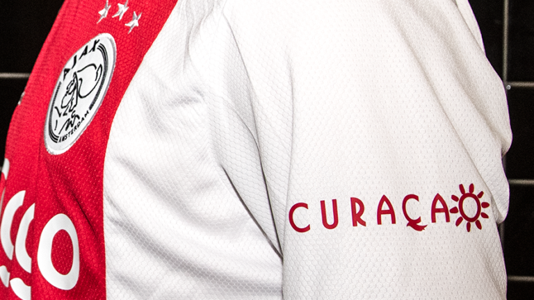 Pic -E shùrt di Ajax ku e logo Curaçao riba e manga